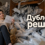 Швея подкладывает дублерин на деталь пиджака перед раскроем, рядом лежат прокладочные материалы и ткань костюма